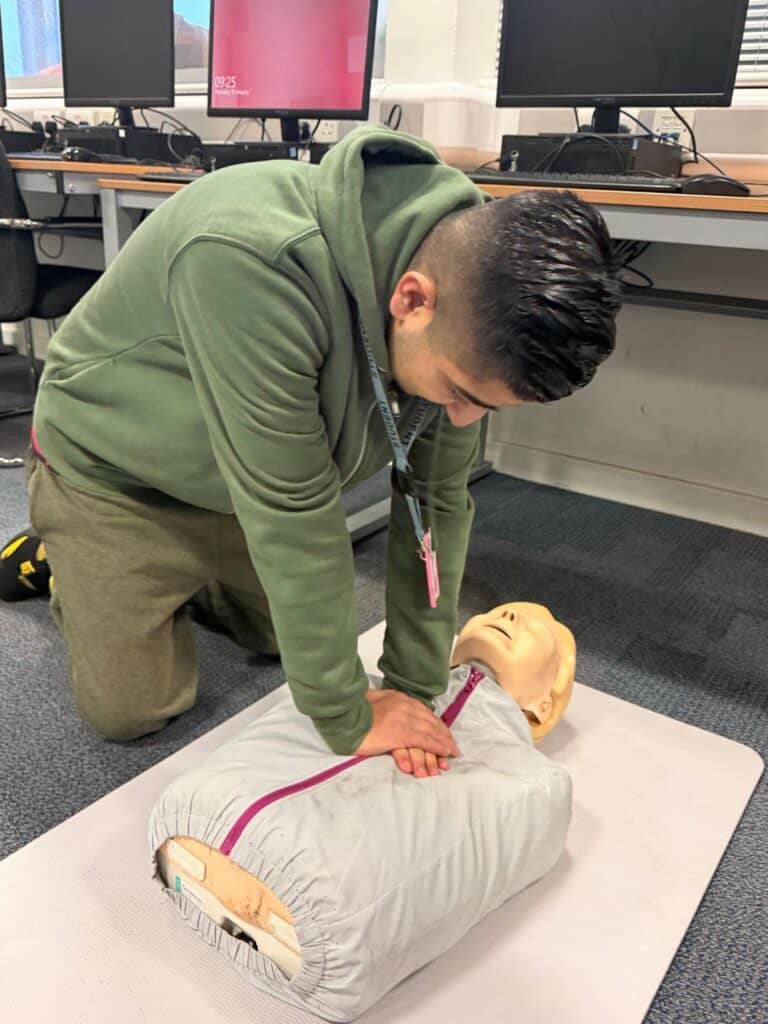 Male student practicing CPR on a dummy