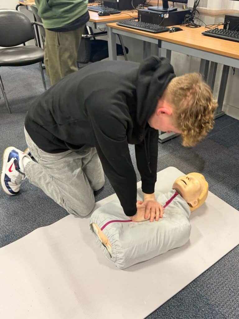 Male student practicing CPR on a dummy
