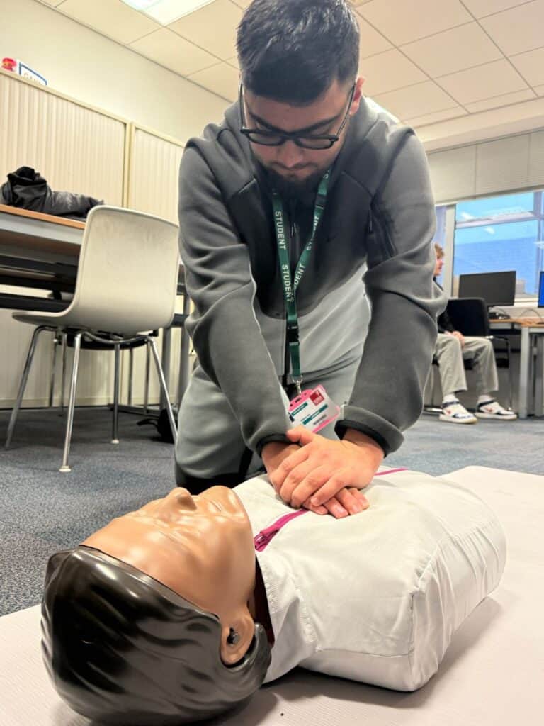 Male student practicing CPR on a dummy